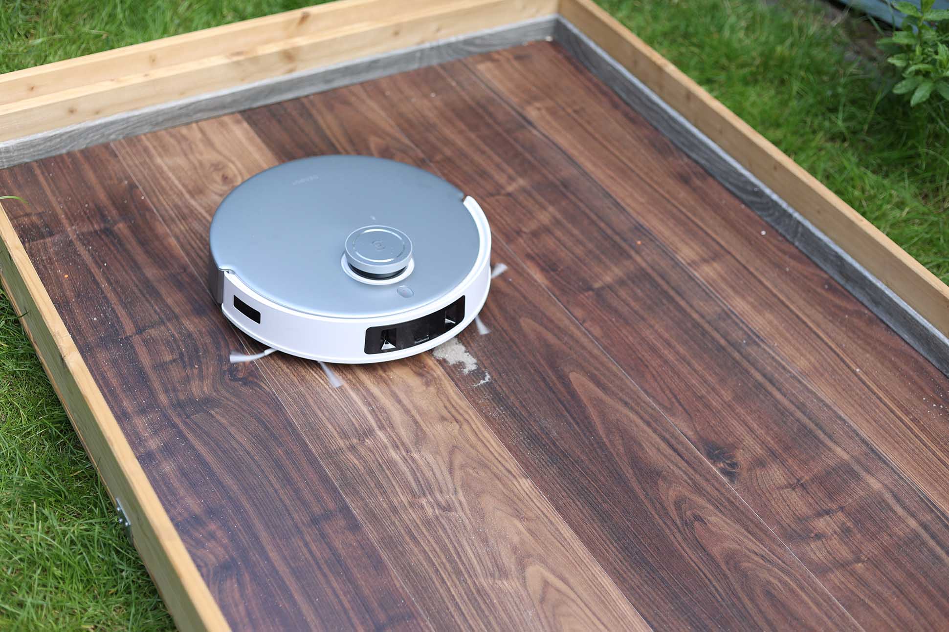 ECOVACS DEEBOT T20 OMNI reinigt im Saugtest Sand auf einem Laminatboden.
